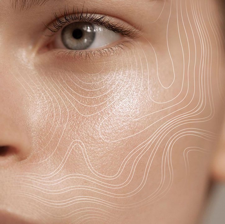 Close-up of a person's cheek and eye with white contour lines mapped across the skin, suggesting facial skin analysis or mapping.