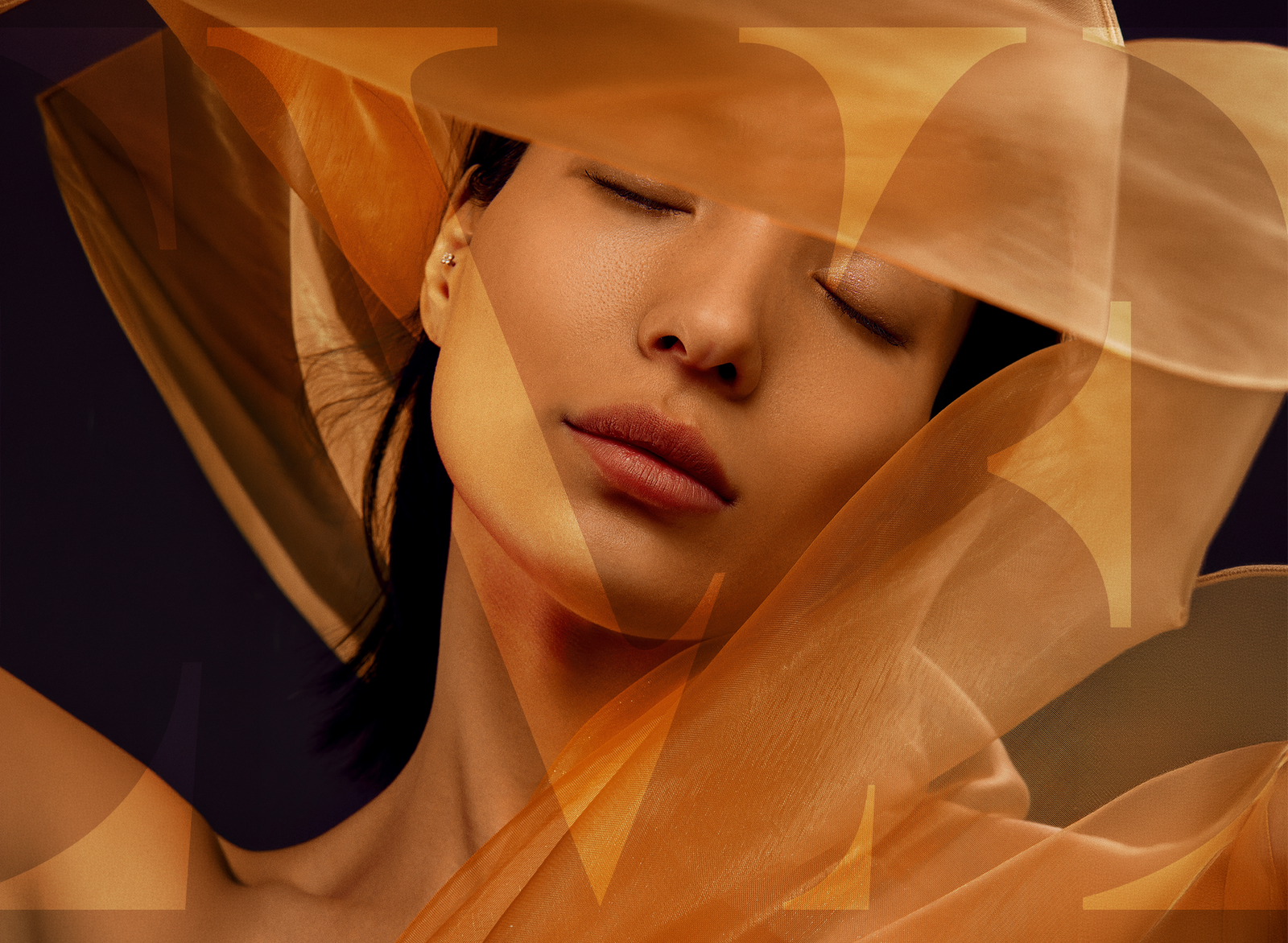 Close-up portrait of a woman with eyes closed, wrapped in sheer orange fabric pieces.